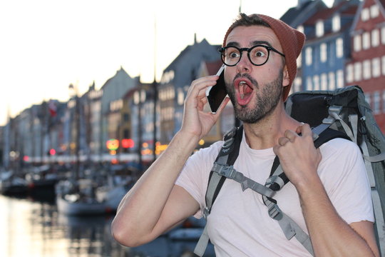 Shocked backpacker getting good news during phone call