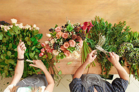 Florist And Assistant In Flower Shop Delivery Make Rose Bouquet, Table Top View