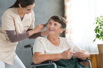 Volunteer brushing pensioner's hair