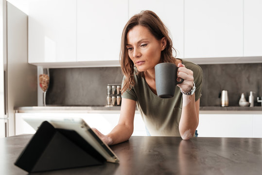Casual woman drinking coffee and using tablet computer