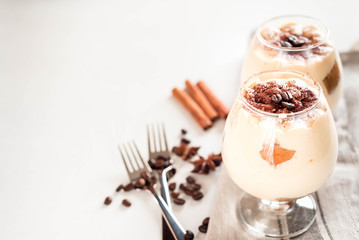 Exquisite Italian dessert tiramisu in cognac glasses on a white