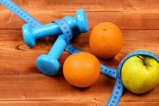 orange, apple with measuring tape, weight dumbbells for diet concept
