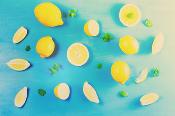 Fresh lemon citrus fruits slices with mint leaves pattern on blue bakground, retro toned