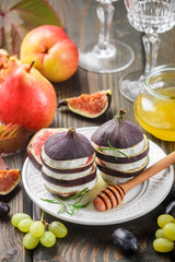 Appetizer of figs and goat cheese with honey. Layered salad of gourmet. Pears, grapes and rosemary on the table. Selective focus