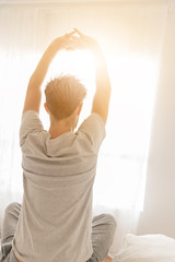 A handsome man stretching in bed after wake up in the morning at home