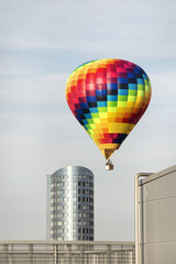 Fototapeta na wymiar Bright Hot air balloon floating low among city buildings. Good for further photo-manipulation.