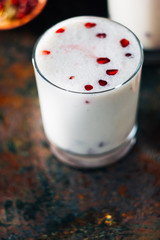 Traditional indian drink - lassi - cold yougurt dessert with the pomegranate seeds.