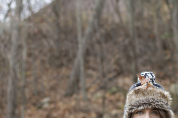 View of half young woman wearing winter hat and leaves. Cropped. Soft focus. Background