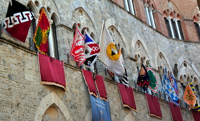 Fahnen der beim Palio startenden Cotraden an einer antiken Fassade