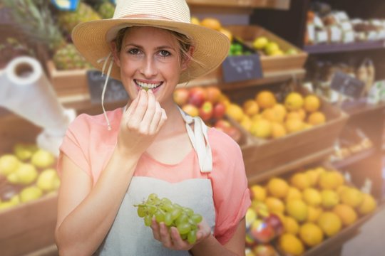 Composite image of portrait of smiling young woman eating grapes
