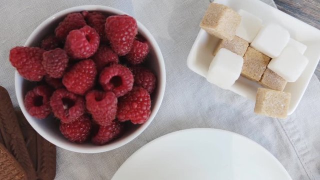 Healthy breakfast - cup of black coffee, bowl of raspberries, bowl of yogurt or milk with fruits, berries and granola or gorp. Top view. Slow pan.