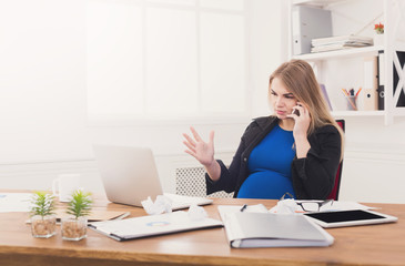 Pregnant business lady at work talking on phone