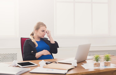 Pregnant woman working on laptop at office