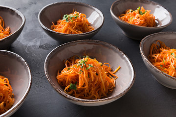 Set of plates with russian korean salad on black background