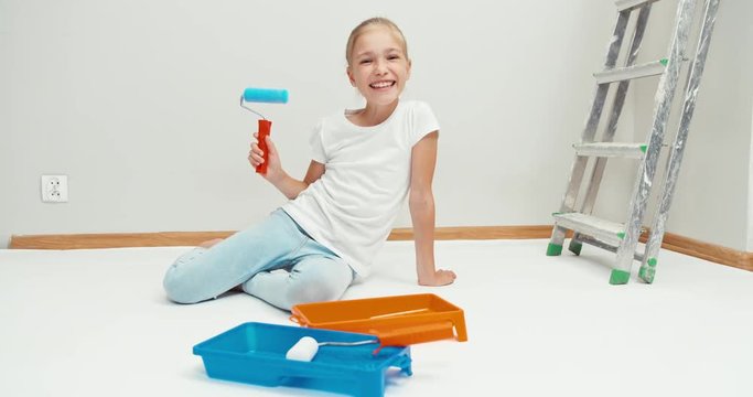 Laughing girl playing with paint roller