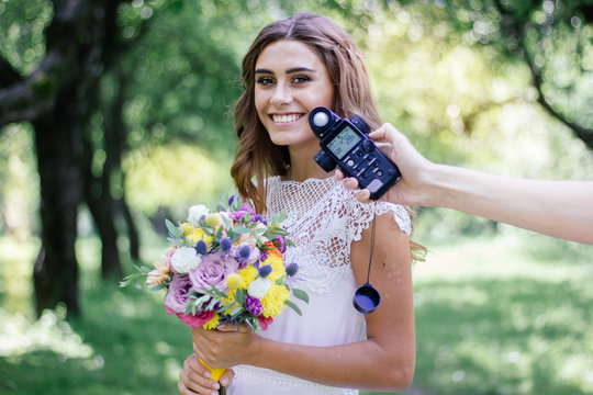 Photographer measuring light with light meter on beautiful girl