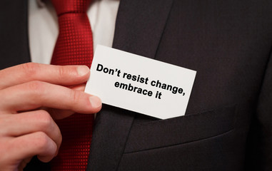 Businessman putting a card with text Dont resist change embrace it in the pocket