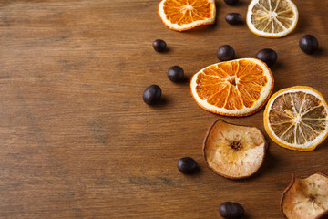 Fototapeta na wymiar Slices of dried fruits on wooden board background