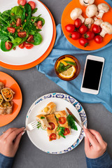 Woman eating healthy food on gray background, top view.