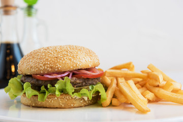 Tasty classical burger with fried potato on white table
