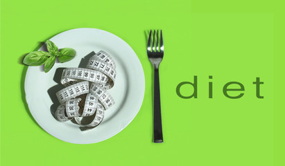concept diet - plate with measure tape - fork - with diet writing on green background