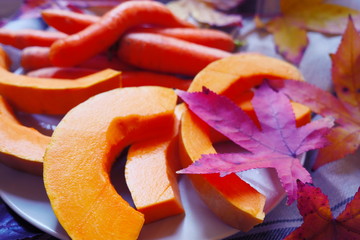 Pumpkin and carrot Slices. Fresh autumn vegetables. Composition of pumpkin and carrot on the wooden cut board. Autumn food composition with yellow leaf. Happy Thanksgiving composition.