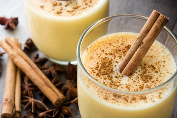 Homemade eggnog with cinnamon on wooden table. Typical Christmas dessert.
