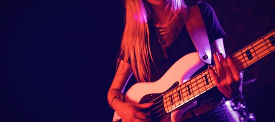Beautiful female guitarist performing in nightclub