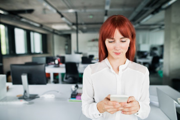 Obraz na płótnie Canvas Businesswoman with smartphone in her office working.