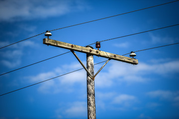 Iceland low power voltage lines in sunny blue sky.