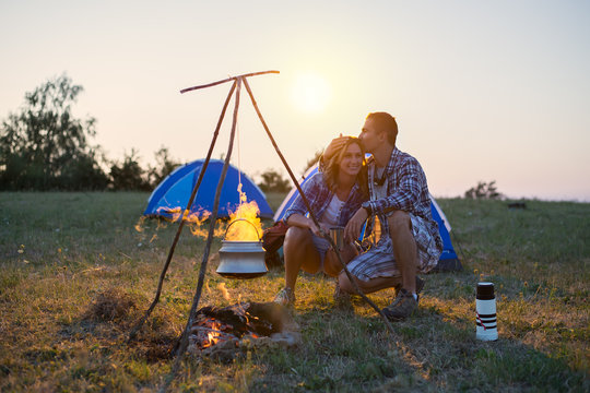 Couple camping at sunset with kettle