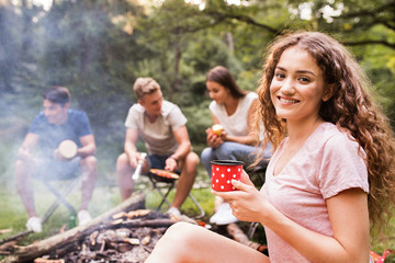 Teenagers camping, cooking meat on bonfire.
