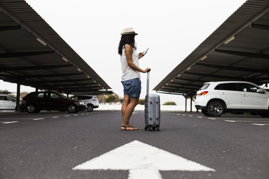 Young woman with travel bag and mobile phone at the parking airport ready for travel. concept. lifestyle