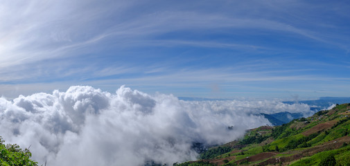 Mist among mountain illuminated by morning sunrise in panorama view.