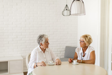 Obraz premium Two older women drinking coffe at home and talking