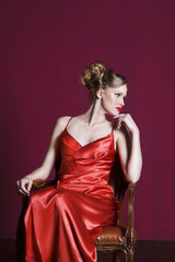 Fototapeta premium Young beautiful blond woman in red dress over red background. Fashion concept.