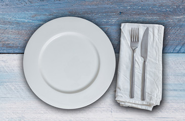 Leerer Teller mit Besteck auf blauem und weißem vintage Holz