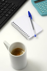 Office desk : PC keyboard, notebook, pen, calculator and coffee cup