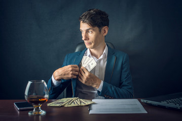 Man Businessman in suit puts money in his pocket. A bribe in the form of dollar bills. Concept of corruption and bribery