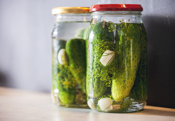 Pickled cucumbers in a jar with spices and herbs close up