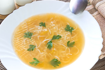Clear soup in plate on old wooden table
