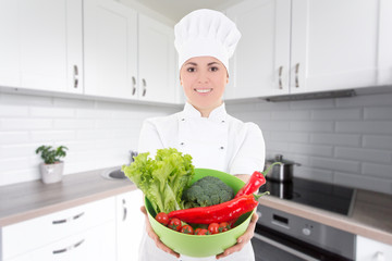 young cook woman in uniform with vegetarian food in modern kitchen