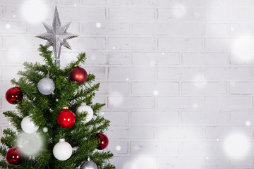 Close up of christmas tree over white brick wall with snow