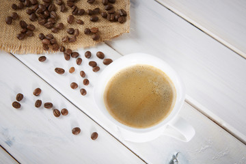 Cup of coffee on a background of coffee beans and a jute bag. 