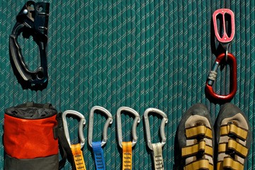 Top view of rock climbing gear laid out beautifully on a green rope. Ascender, chalk bag,...