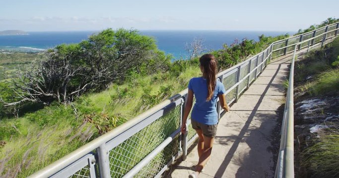 Female hiker walking on footpath of observation point at Diamond Head State Monument. Young woman is enjoying sea view during summer vacation. She is enjoying sunny day. Oahu. Hawaii. USA.