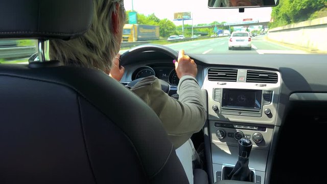 Middle aged woman drives a car in the city in summer day 