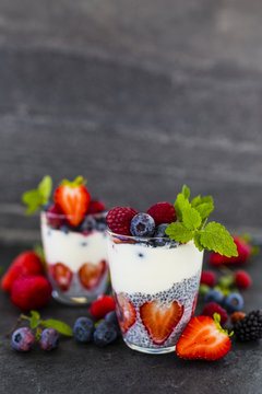 Yogurt with fresh berries fruit and chia seeds on dark background with space for text.