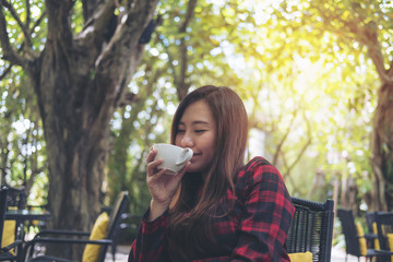 Fototapeta premium Closeup image of a beautiful Asian woman using and looking at smart phone with feeling bored while waiting for someone in modern green cafe