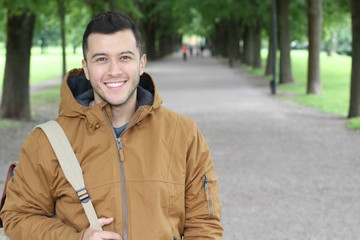 Trendy male with a winter outfit smiling in the park